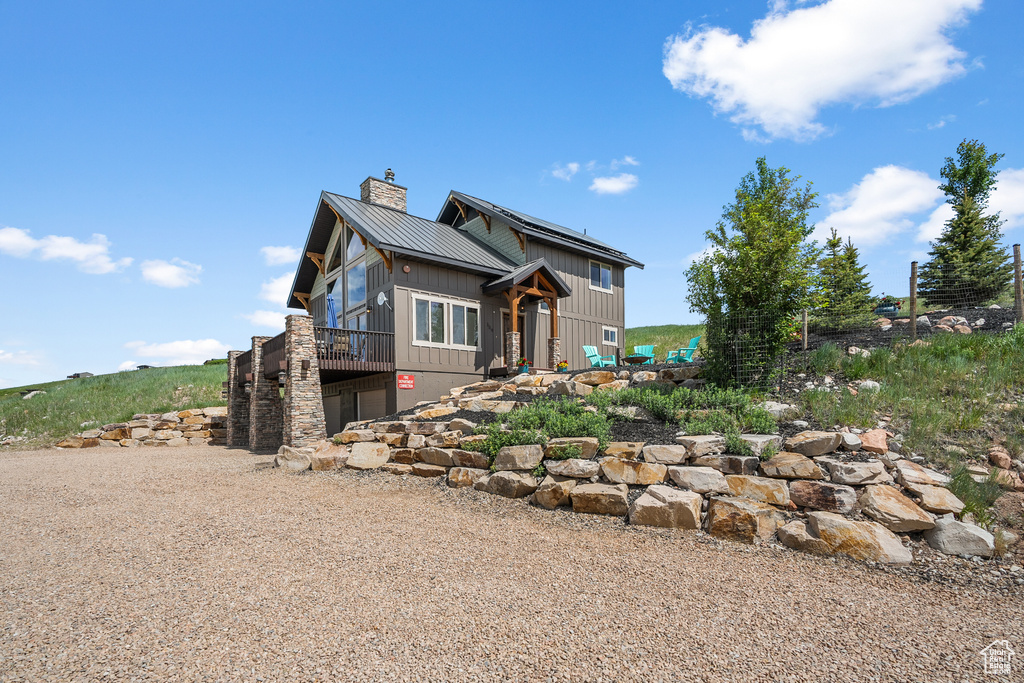 Rear view of property with a chimney, metal roof, and a wooden deck