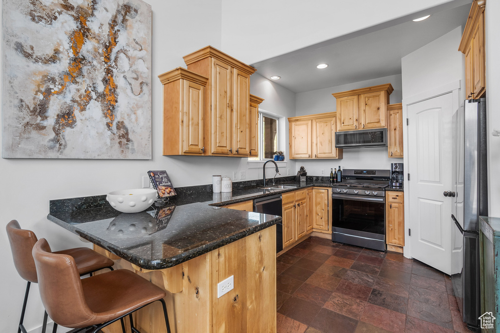 Kitchen featuring stainless steel appliances, a peninsula, recessed lighting, a sink, and dark stone counters