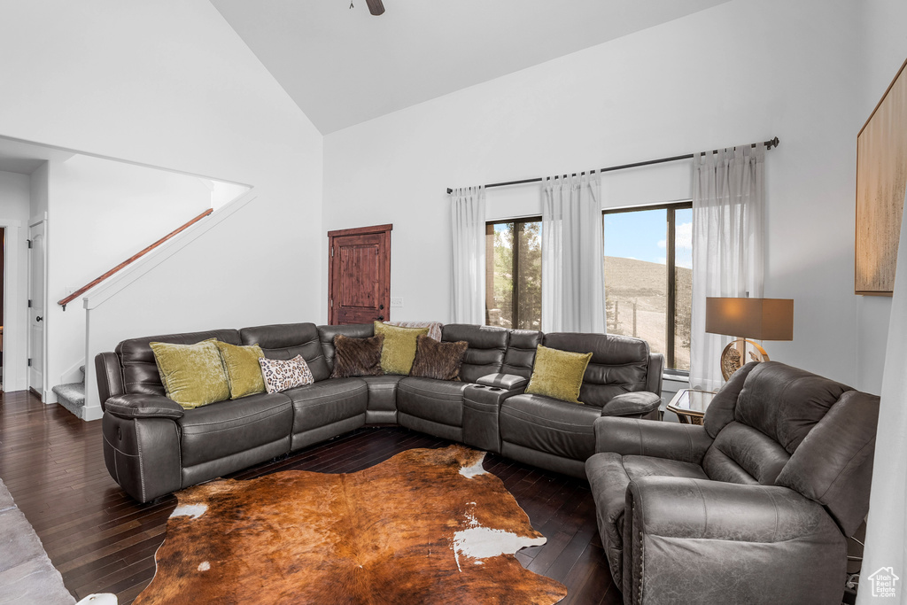 Living room featuring high vaulted ceiling, dark wood-style floors, stairway, and ceiling fan