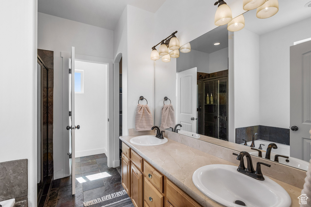 Full bath with a shower stall, stone tile floors, double vanity, and a bath