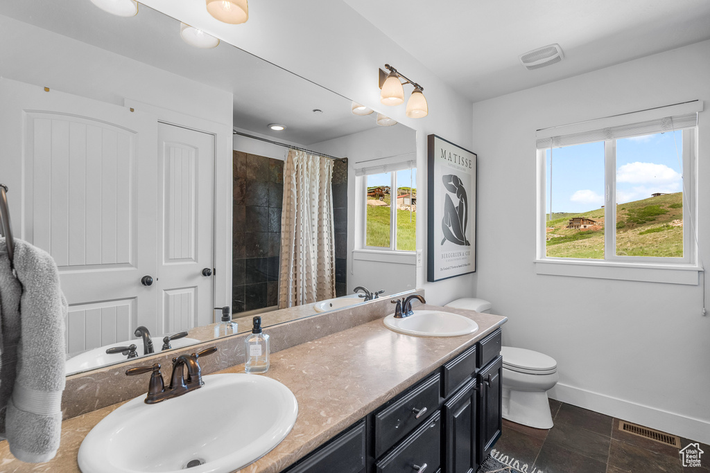 Full bathroom featuring double vanity, toilet, a shower with curtain, and baseboards