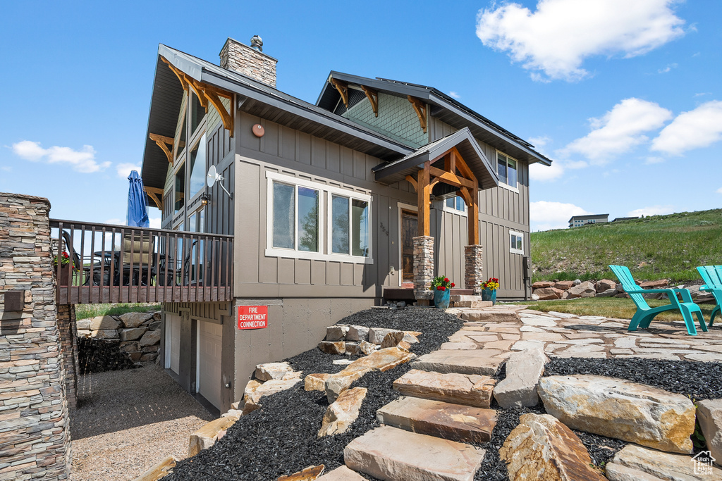 View of front of home featuring a chimney, a balcony, and board and batten siding