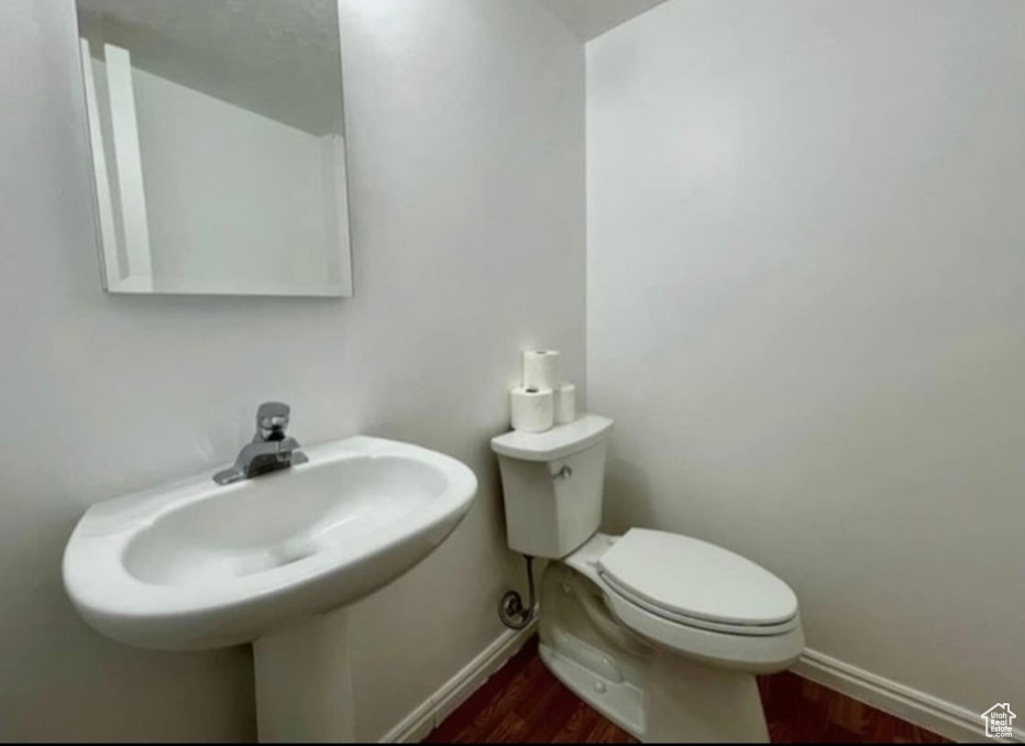 Bathroom featuring baseboards, wood finished floors, and toilet