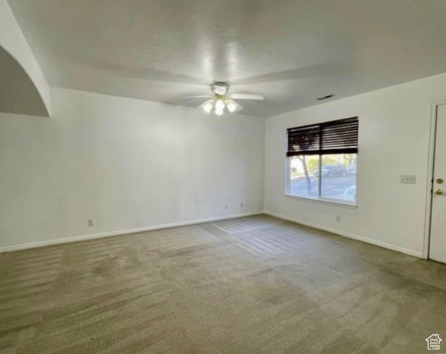 Spare room featuring ceiling fan, carpet floors, and baseboards