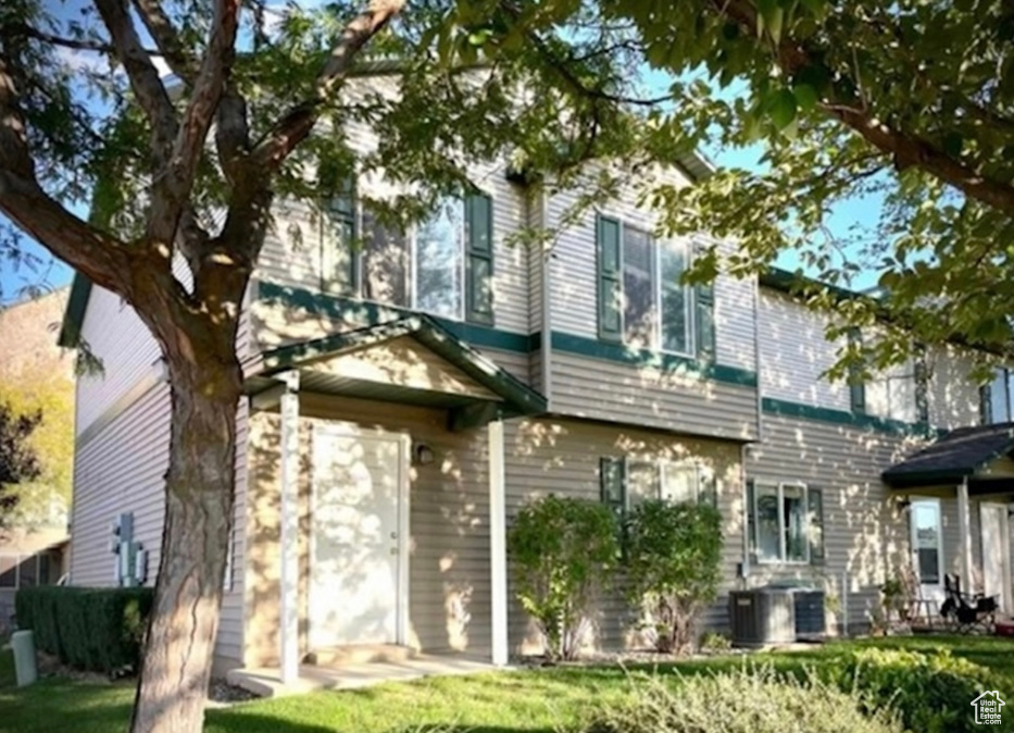 Rear view of property featuring cooling unit and a yard