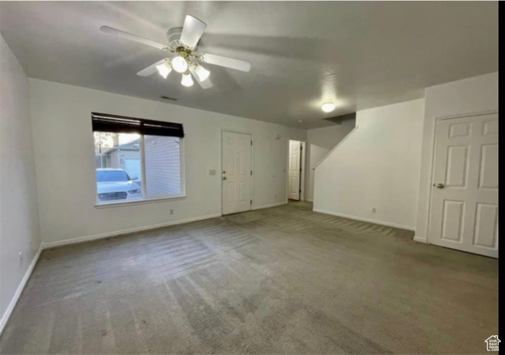 Carpeted empty room featuring baseboards and ceiling fan