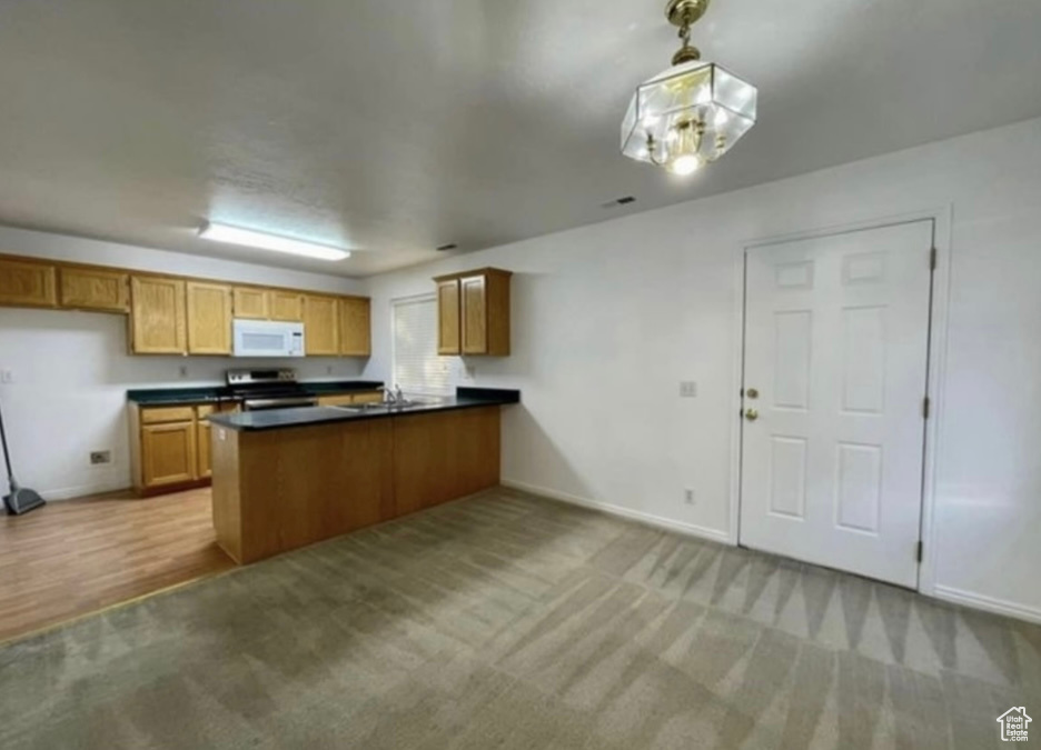 Kitchen featuring white microwave, stainless steel range with electric stovetop, a peninsula, and baseboards