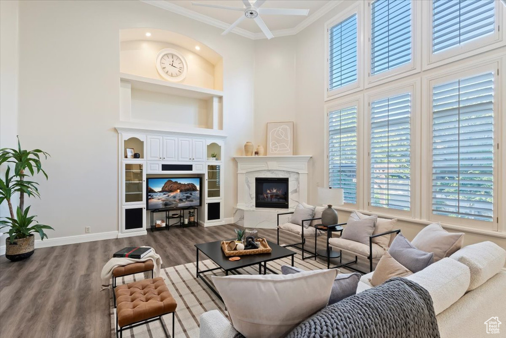 Living room featuring built in features, wood finished floors, a ceiling fan, ornamental molding, and baseboards