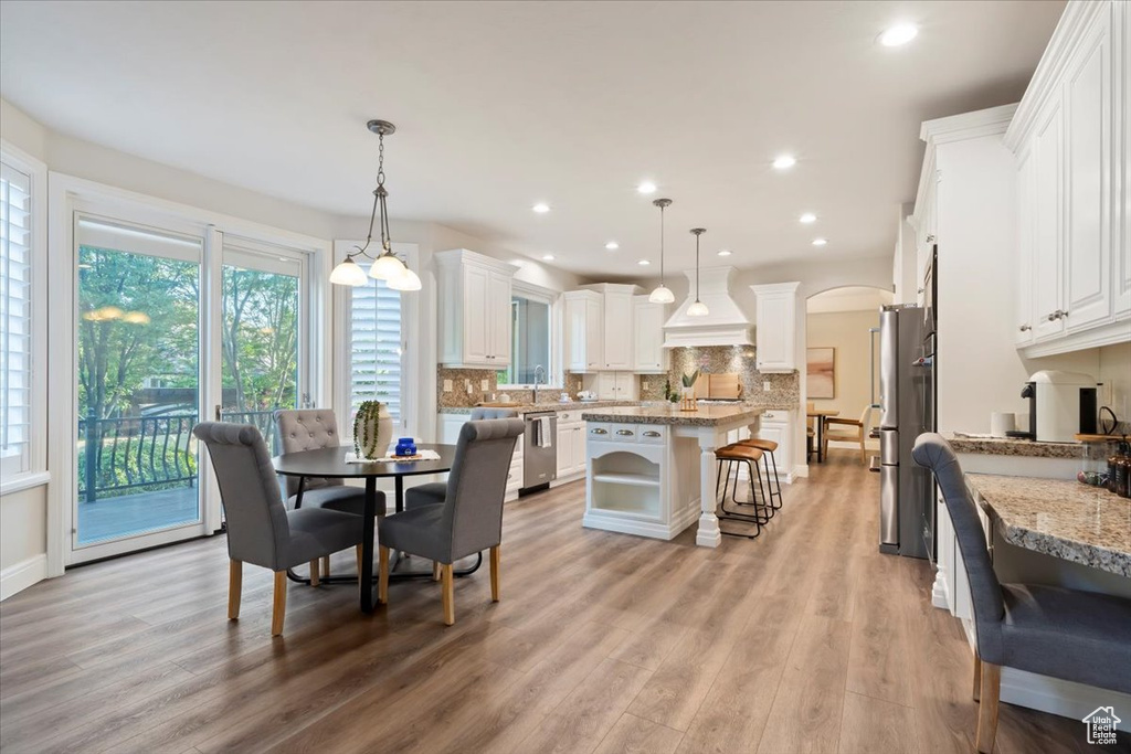Dining area with arched walkways, light wood-style floors, and recessed lighting