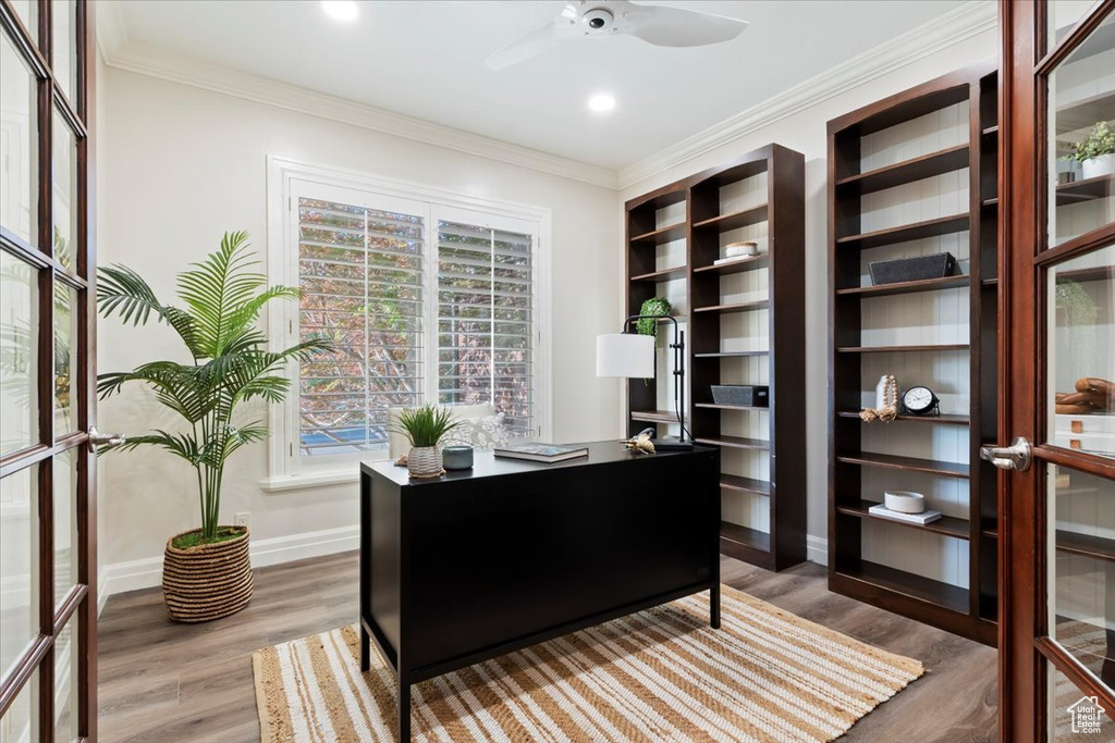 Home office featuring plenty of natural light, wood finished floors, a ceiling fan, baseboards, and crown molding