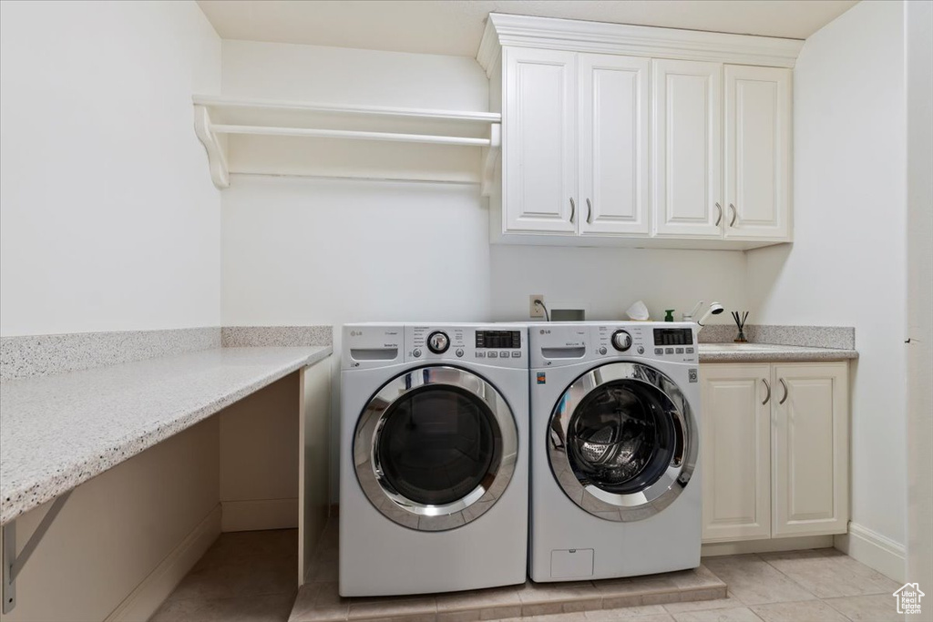Laundry room featuring cabinet space, washer and dryer, and light tile patterned flooring