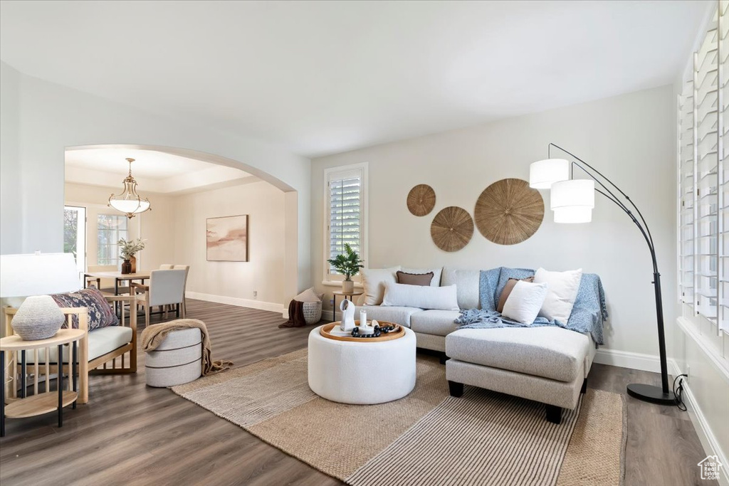 Living area with arched walkways, wood finished floors, and baseboards