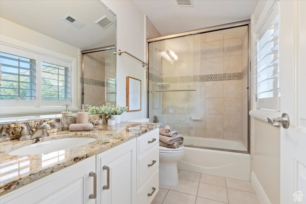 Full bathroom with tile patterned flooring, vanity, toilet, and enclosed tub / shower combo