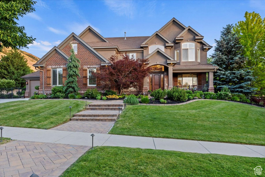 View of front of property with brick siding, a front yard, and stucco siding