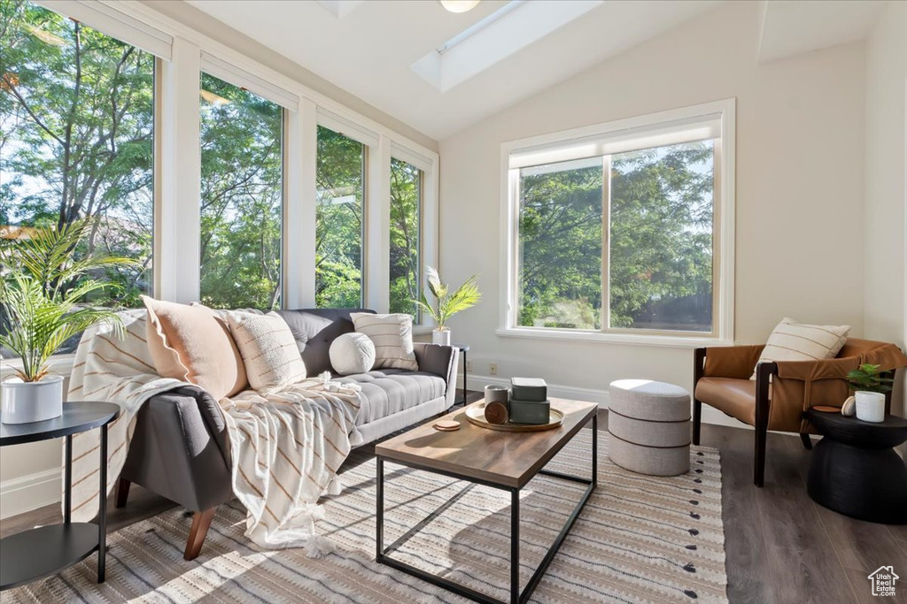 Sunroom with lofted ceiling, a skylight, wood finished floors, and baseboards