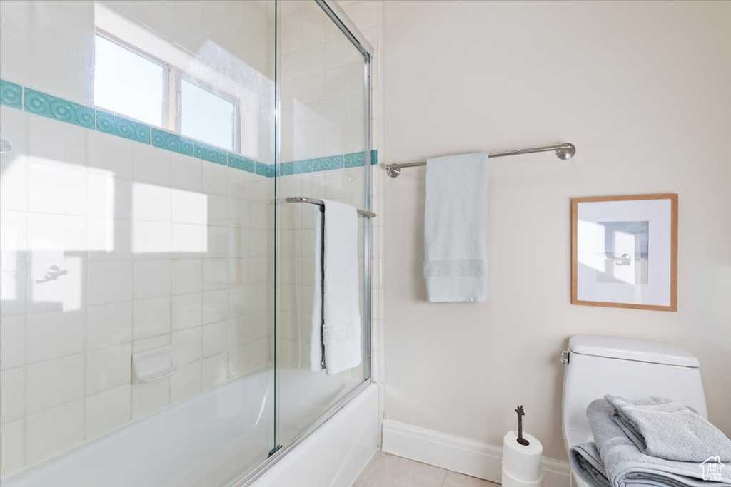Bathroom with bath / shower combo with glass door, baseboards, and toilet