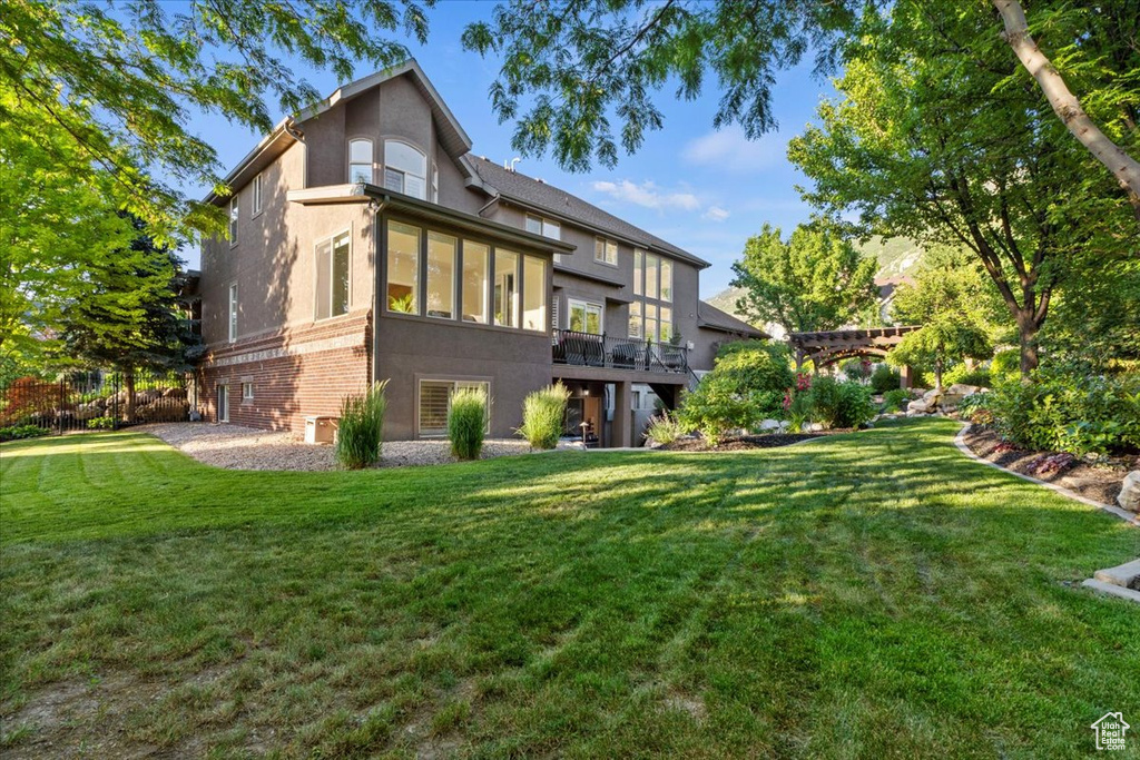 Rear view of house featuring stucco siding, a yard, and brick siding