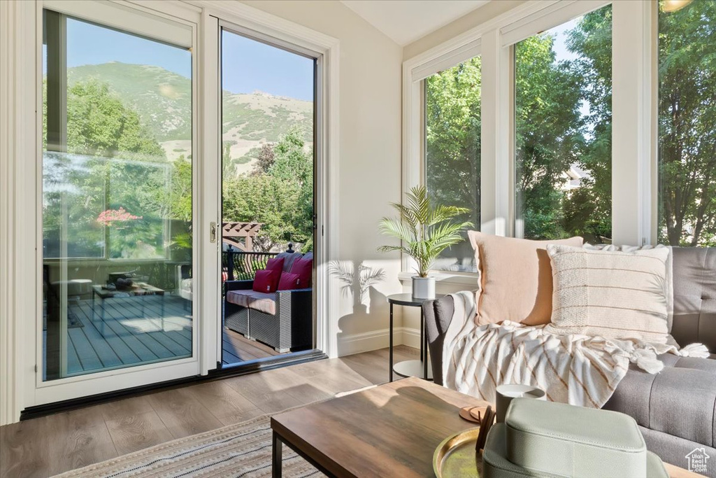 Sunroom with wood finished floors, lofted ceiling, and baseboards