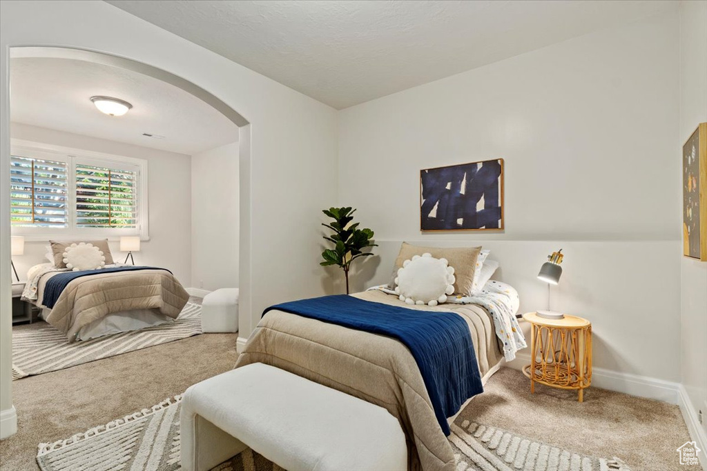 Carpeted bedroom with arched walkways and baseboards
