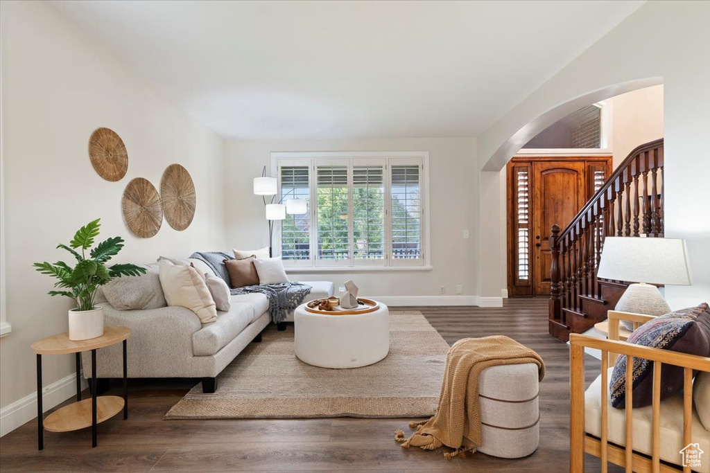 Living area featuring arched walkways, wood finished floors, and baseboards