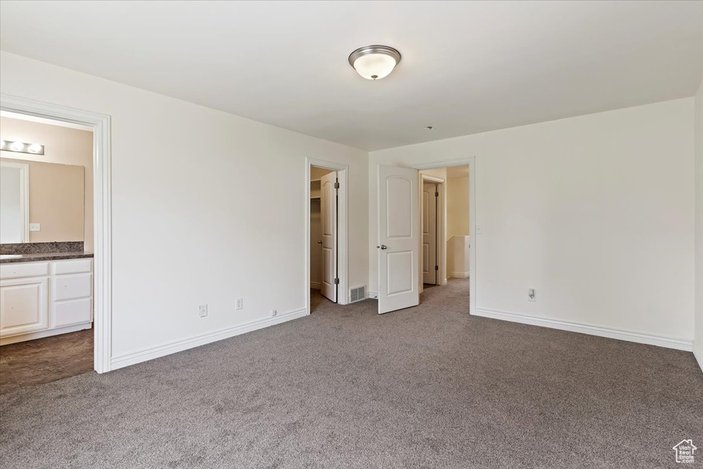 Unfurnished bedroom with carpet, baseboards, and ensuite bath