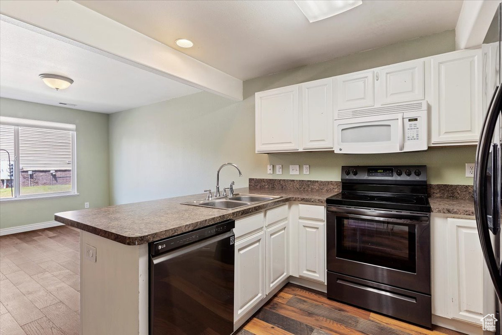 Kitchen with white microwave, dishwasher, electric range, a sink, and a peninsula