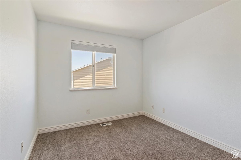 Spare room featuring carpet flooring and baseboards