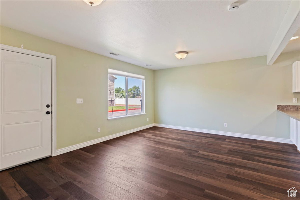 Unfurnished living room with dark wood finished floors and baseboards