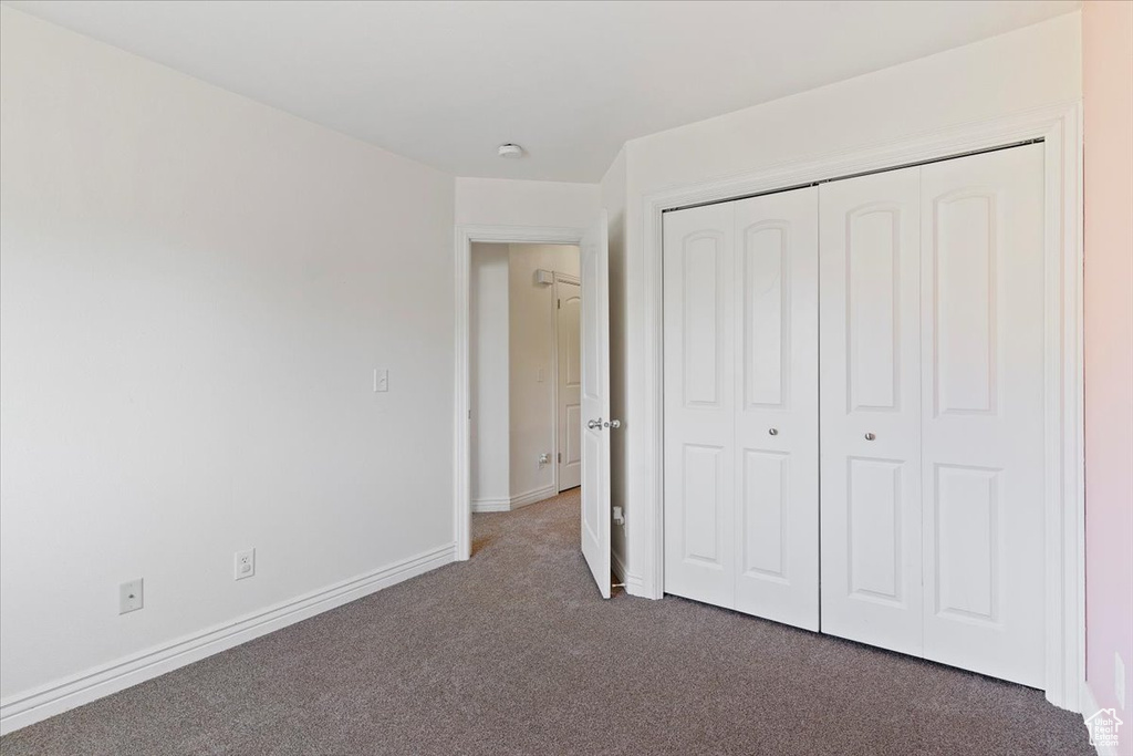 Unfurnished bedroom with carpet flooring, a closet, and baseboards