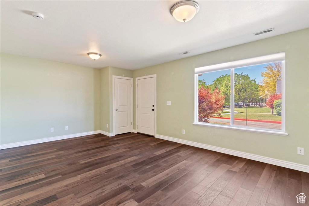 Unfurnished room featuring baseboards, dark wood-style floors, and a smoke detector
