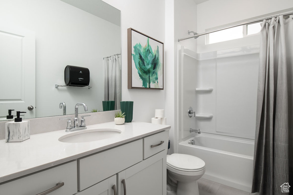 Bathroom featuring vanity, shower / bathtub combination with curtain, and toilet