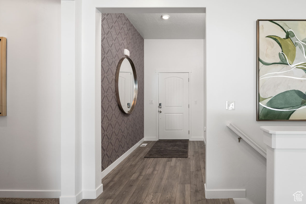Foyer entrance featuring wallpapered walls, baseboards, and wood finished floors