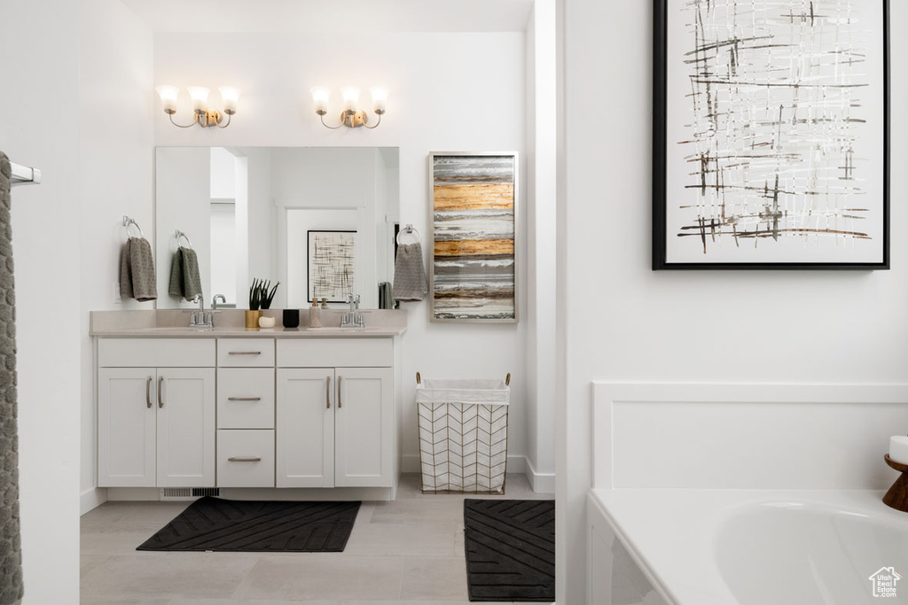 Bathroom with double vanity, a bathtub, baseboards, and tile patterned floors