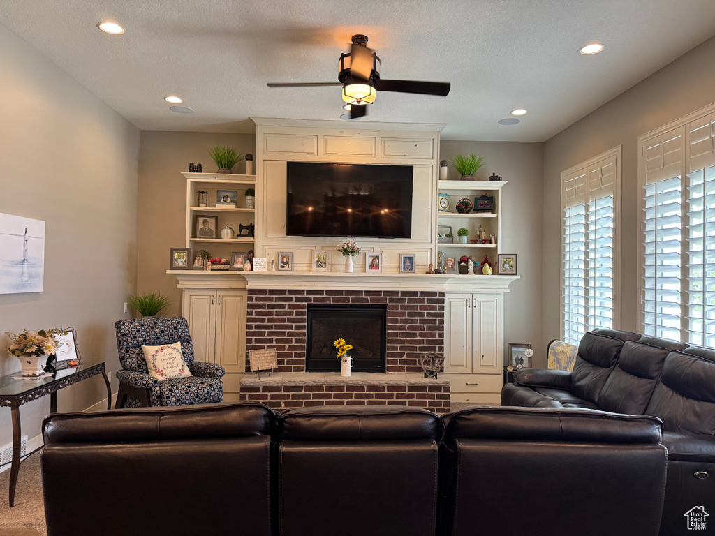Living room featuring a brick fireplace, ceiling fan, and recessed lighting