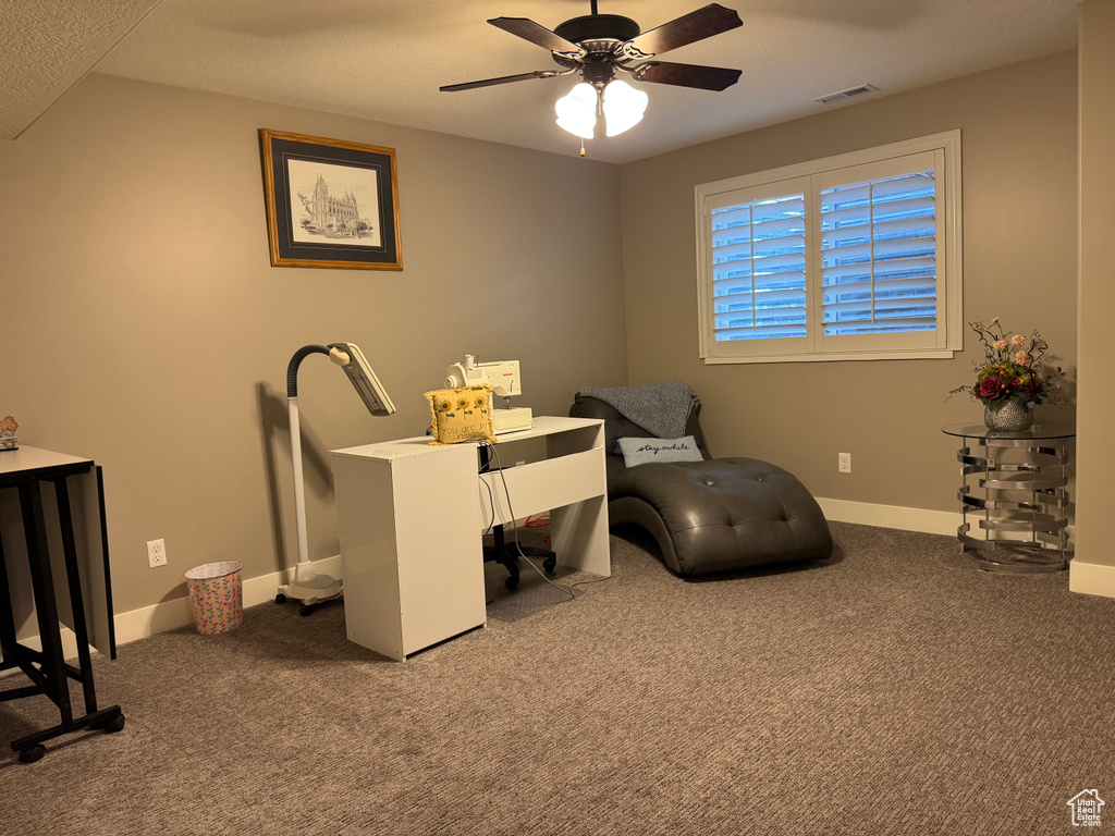 Carpeted office space with a ceiling fan and baseboards