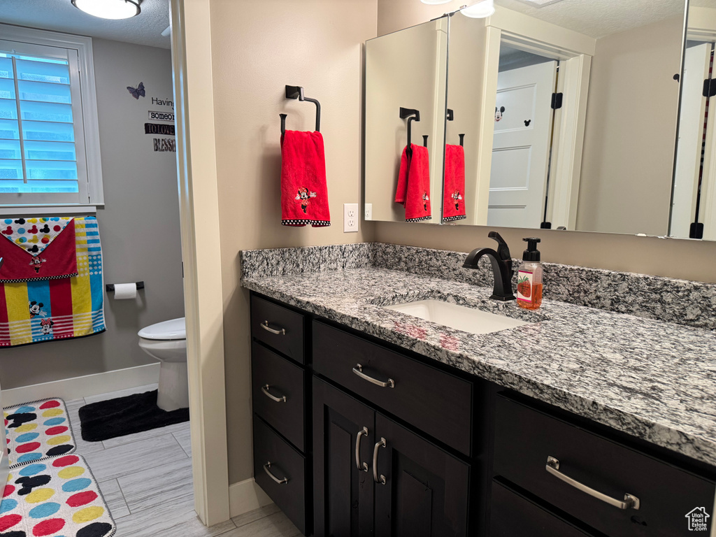 Bathroom featuring baseboards, vanity, and toilet