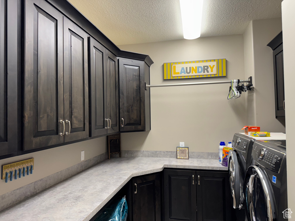 Laundry area featuring cabinet space, washing machine and clothes dryer, and a textured ceiling