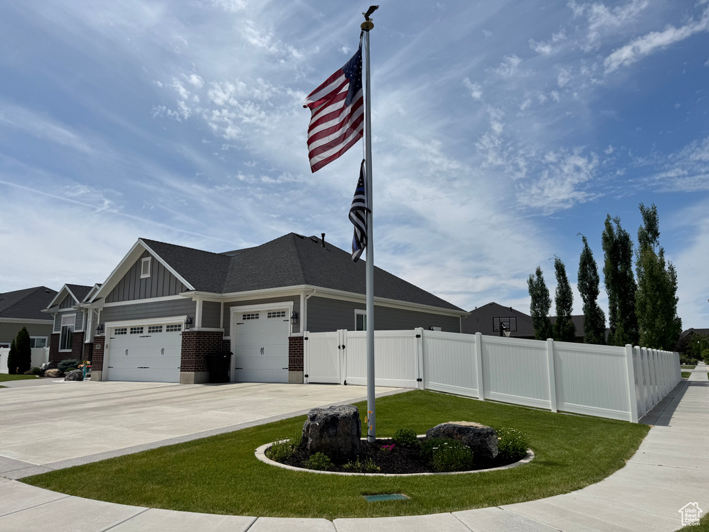 View of front of home featuring an attached garage, board and batten siding, a gate, and driveway
