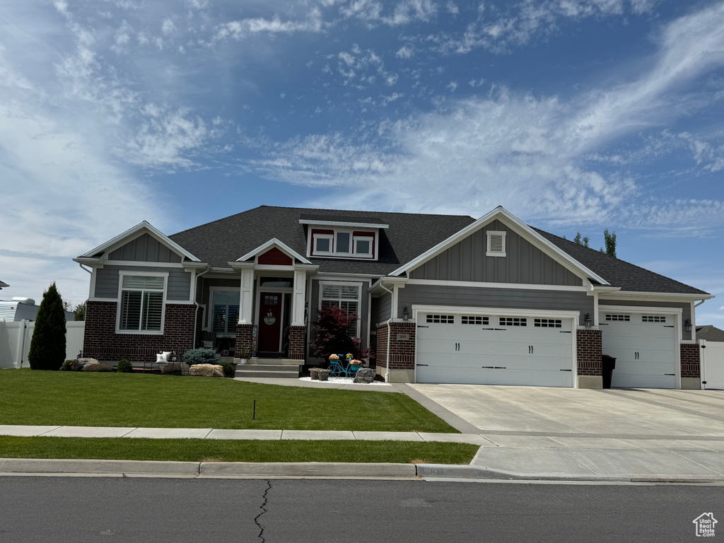 Craftsman inspired home with a garage, brick siding, driveway, roof with shingles, and board and batten siding