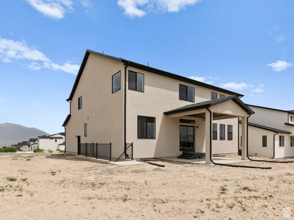 Back of property with stucco siding, a patio, and a mountain view