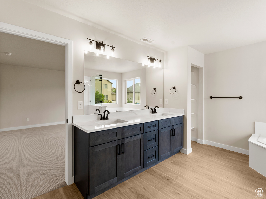 Full bathroom with double vanity, wood finished floors, and a bathtub