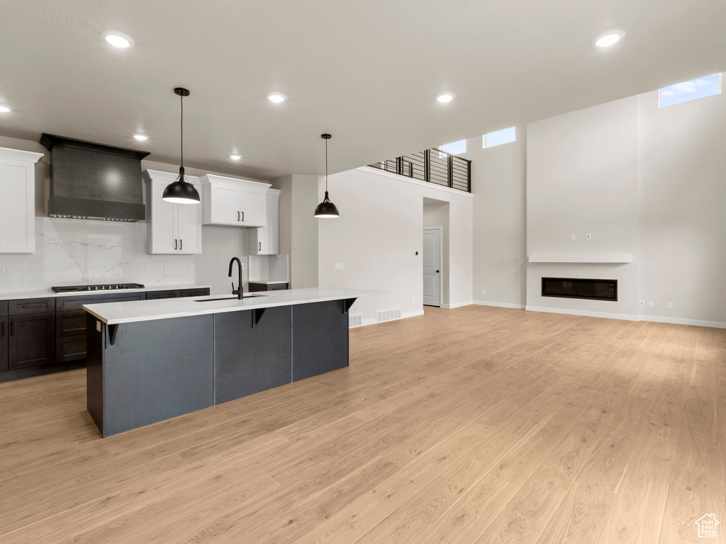 Kitchen featuring premium range hood, light countertops, a large island, a breakfast bar area, and recessed lighting