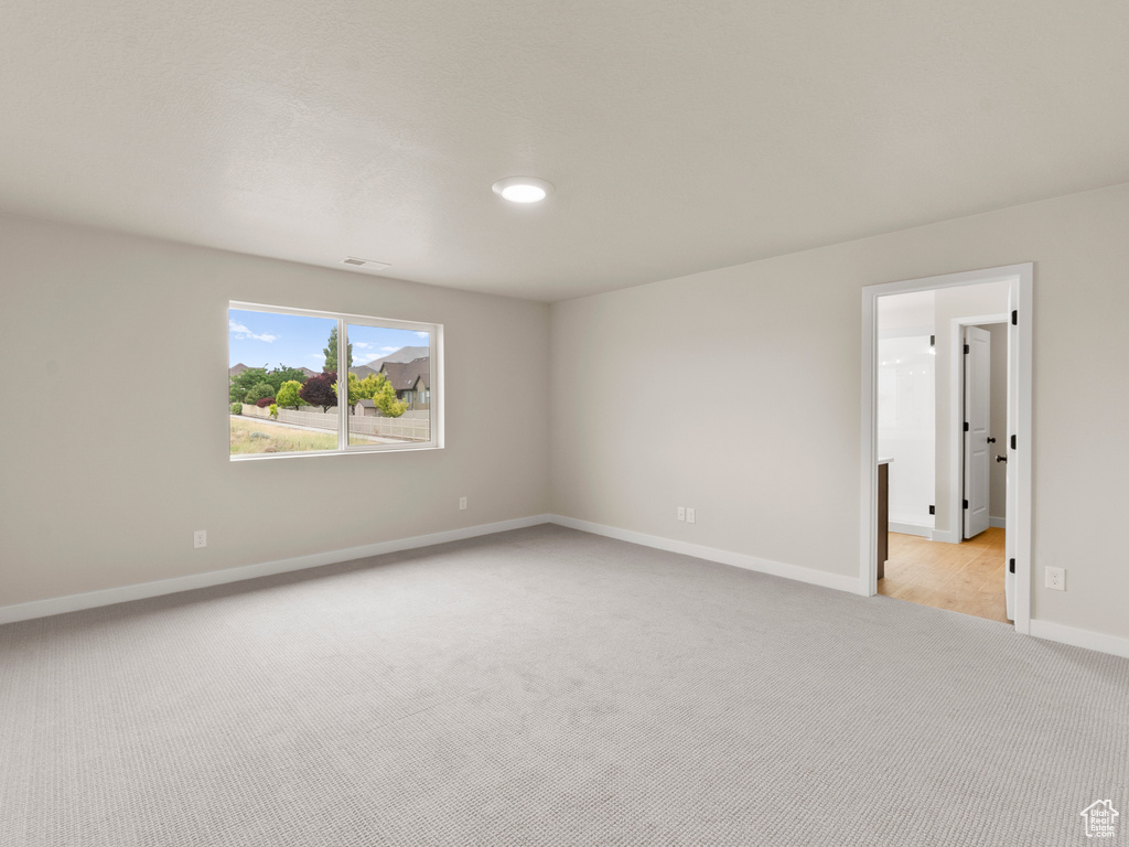 Spare room featuring light colored carpet and baseboards