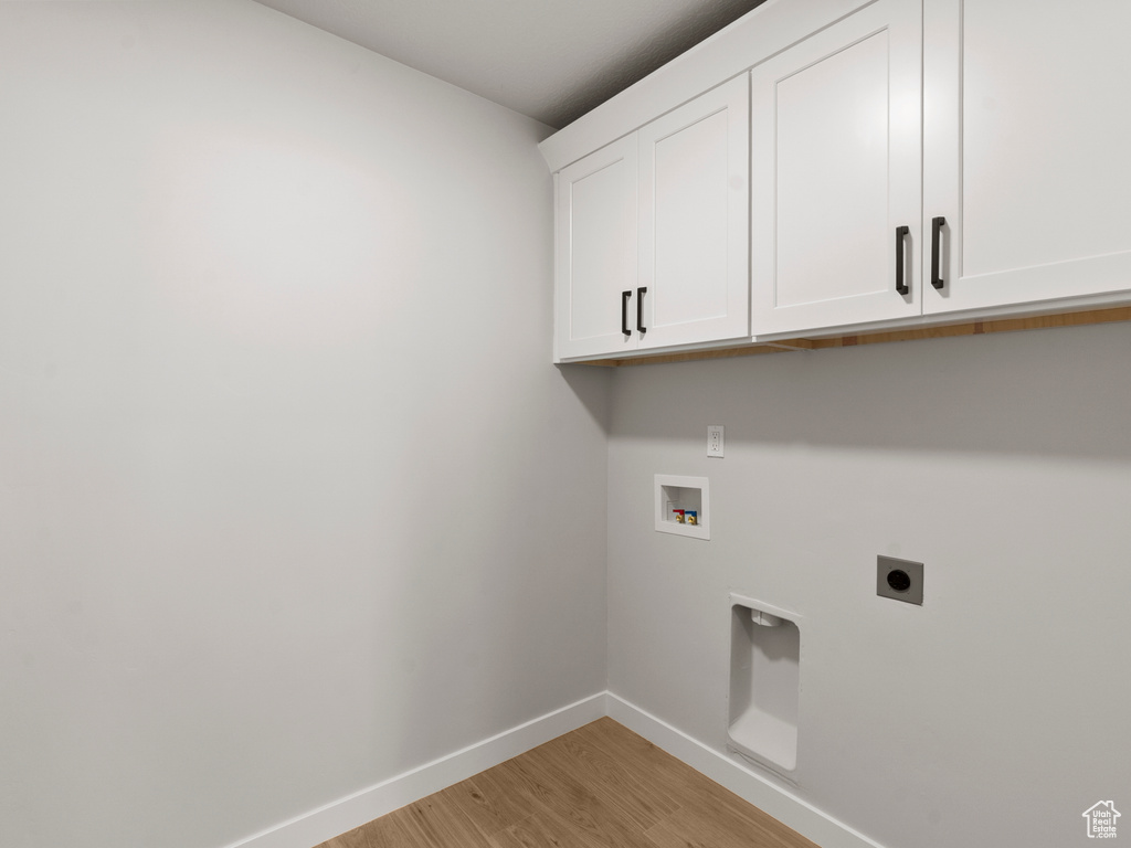 Laundry area featuring electric dryer hookup, cabinet space, light wood-style floors, and hookup for a washing machine