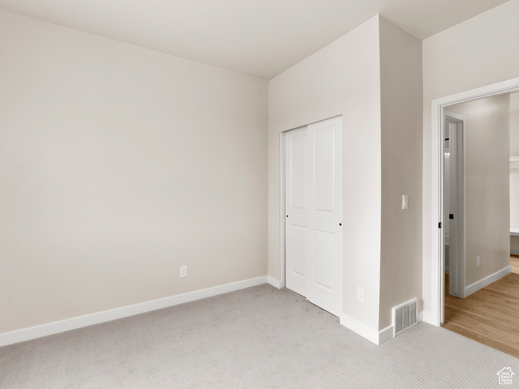 Unfurnished bedroom with light colored carpet and a closet