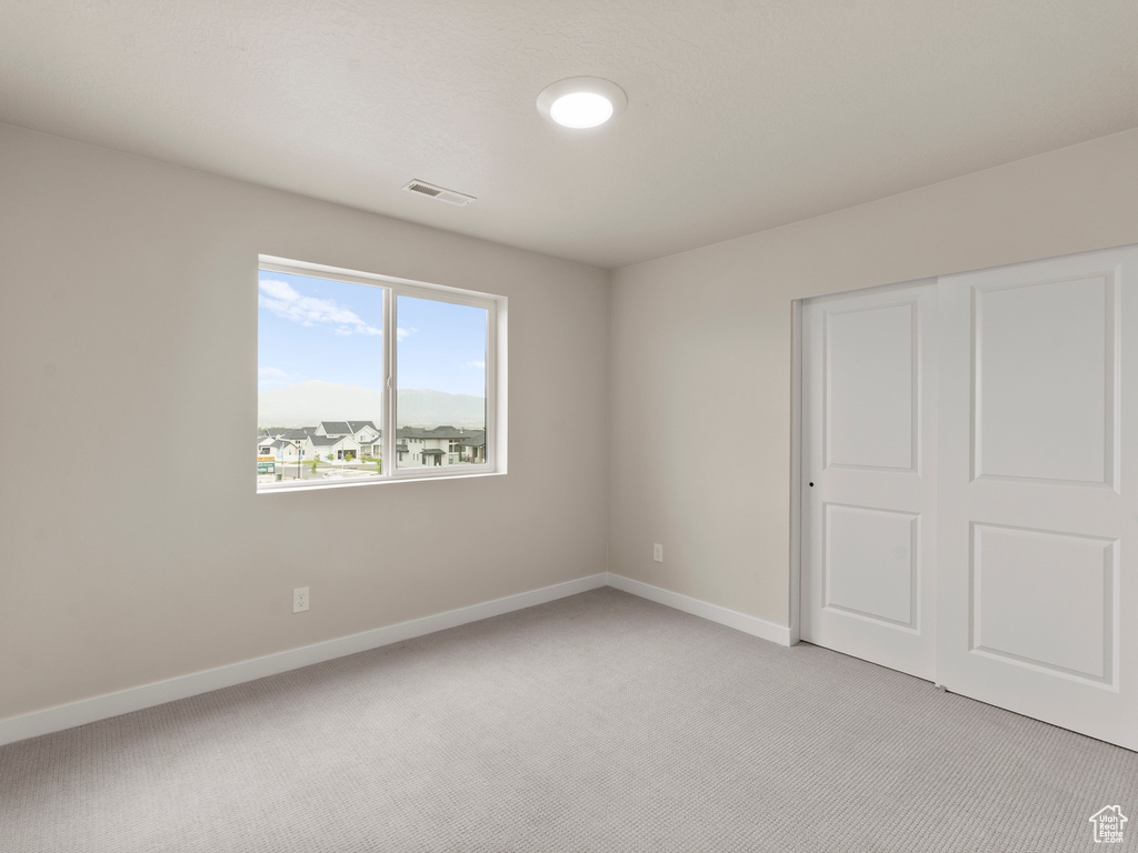 Unfurnished bedroom featuring light carpet and a closet