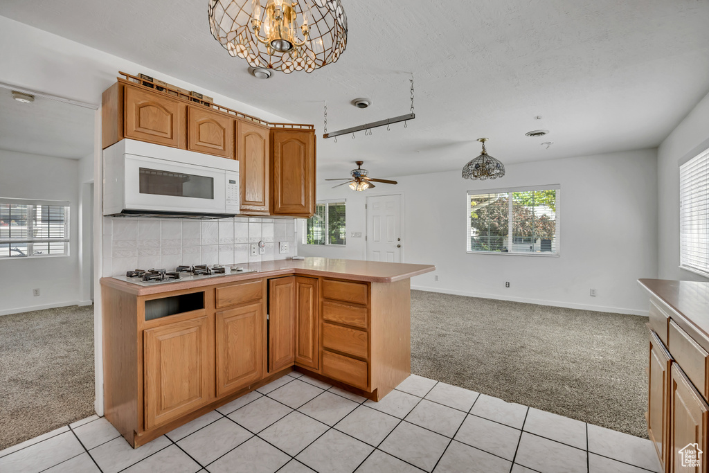 Kitchen featuring white appliances, light carpet, open floor plan, and baseboards