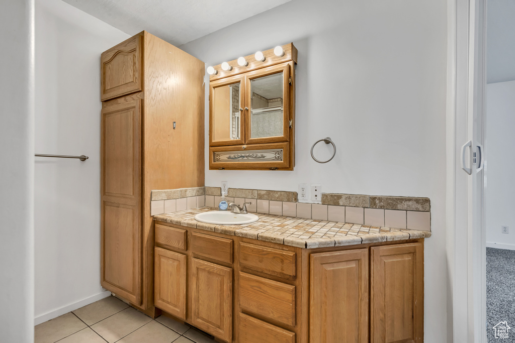 Bathroom featuring vanity, tile patterned floors, and baseboards