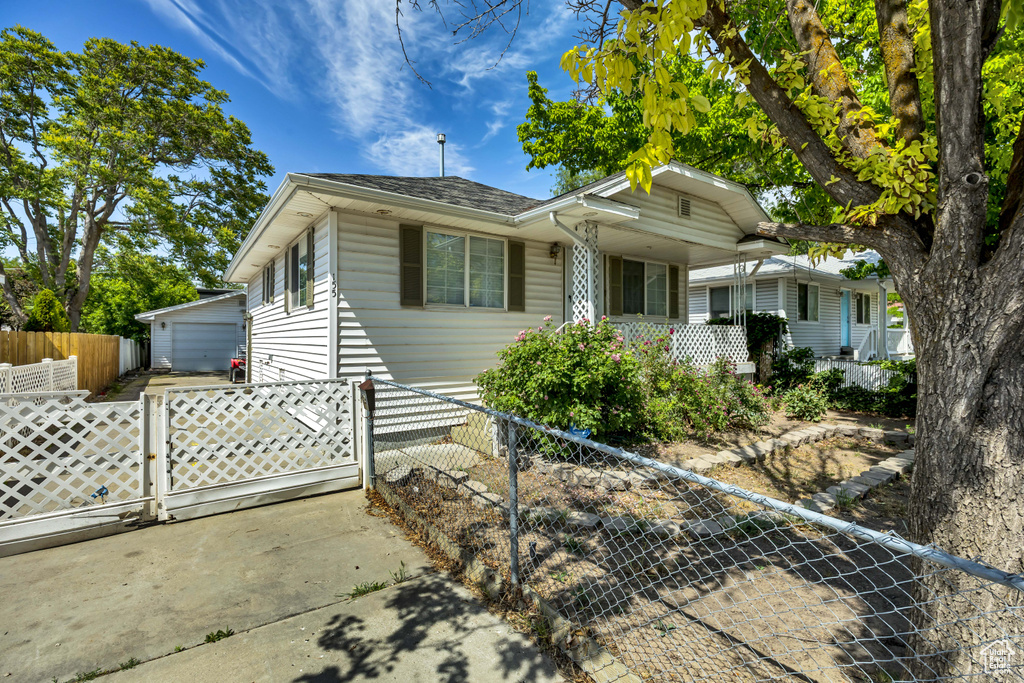 Bungalow with a detached garage, an outdoor structure, and a gate