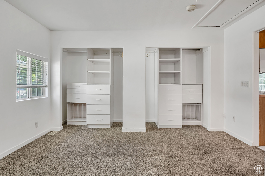 Unfurnished bedroom with two closets, carpet floors, and baseboards